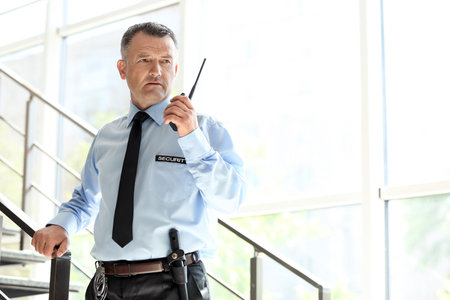 Male security guard using portable radio transmitter indoorsの写真素材