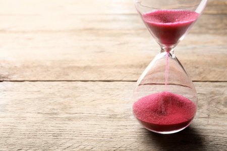 Hourglass with flowing sand on table. time management