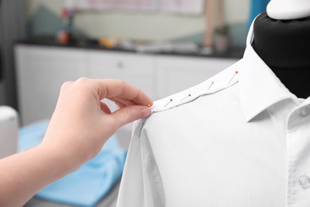 Seamstress putting pins into semi-ready shirt in tailor workshop, closeupの写真素材