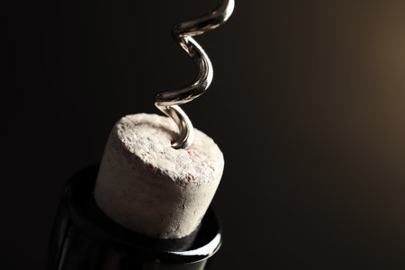 Opening bottle of wine with corkscrew on dark background, closeupの写真素材