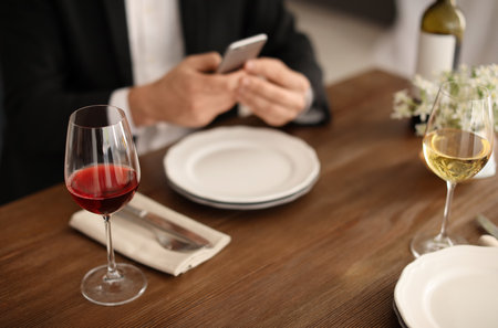 Man with glass of wine at table in restaurantの写真素材