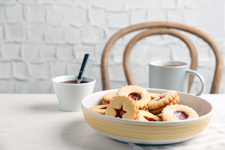 Traditional Christmas Linzer cookies with sweet jam and cup of tea on tableの写真素材