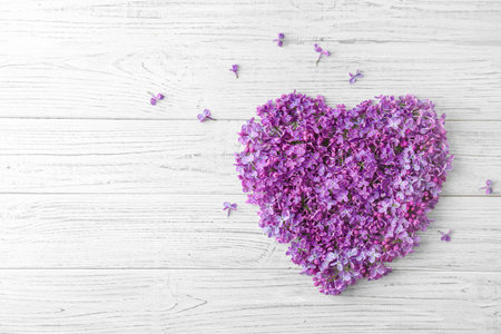 Heart made of blossoming lilac on wooden background, top view. spring flowersの写真素材