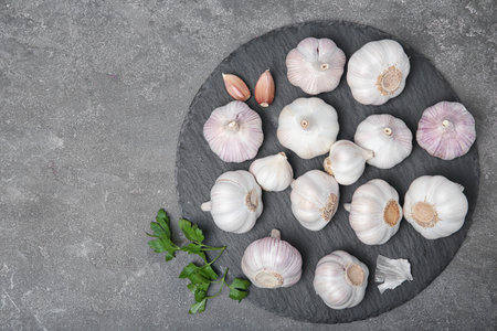 Slate plate with fresh garlic on gray background, top viewの写真素材