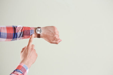 Young man with wrist watch on gray background. time concept