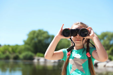 Little girl with binoculars outdoors. Summer campの写真素材