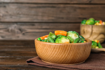Bowl with different frozen vegetables on wooden tableの写真素材