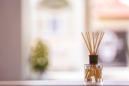 Aromatic reed air freshener on table against blurred background