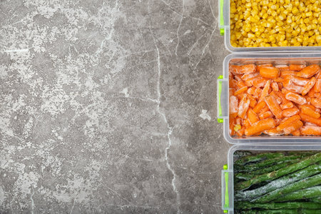 Plastic containers with different frozen vegetables on table, top viewの写真素材