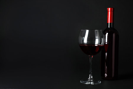 Bottle and glass of expensive red wine on dark backgroundの写真素材