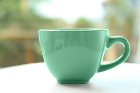 Mint green cup on table against blurred backgroundの写真素材