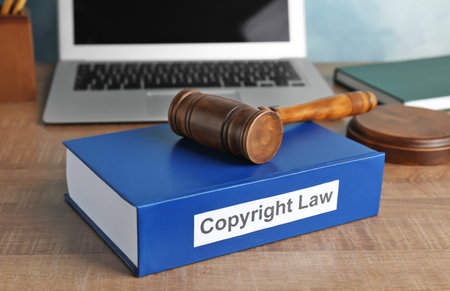 Book with words COPYRIGHT LAW and gavel on table