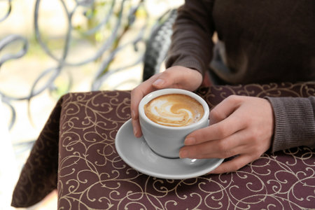 Young woman with cup of delicious coffee at tableの写真素材