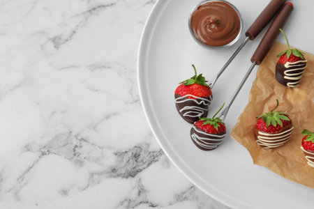 Plate with chocolate covered strawberries on marble background, top viewの写真素材
