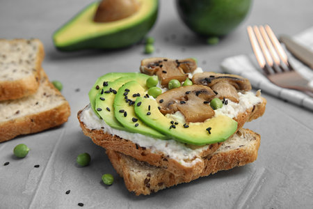 Crisp toast with sliced avocado, cream cheese and mushroom on table, closeupの写真素材