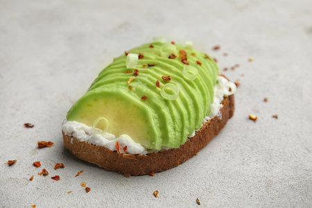 Crisp rye toast with sliced avocado and cream cheese on tableの写真素材