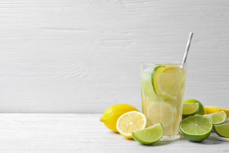 Glass of natural lemonade with citrus fruits on table