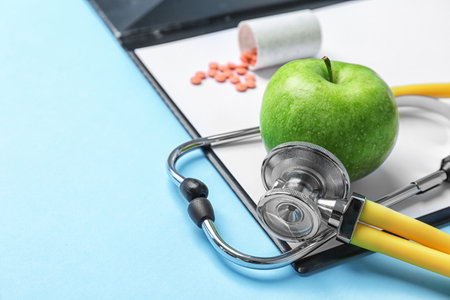 Composition with stethoscope, clipboard, pills and apple on color background. medical equipmentの写真素材