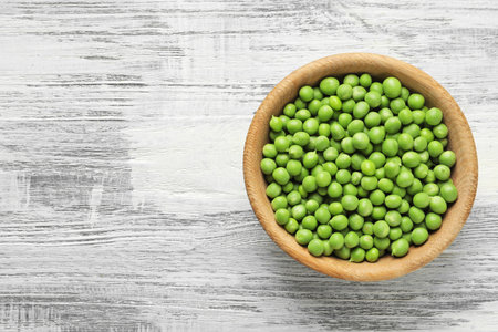 Plate with green peas on wooden background, top viewの写真素材