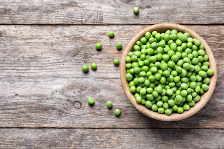 Bowl with delicious fresh green peas on wooden table, top viewの写真素材