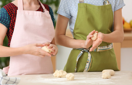 Mother and daughter preparing dough at table, closeup