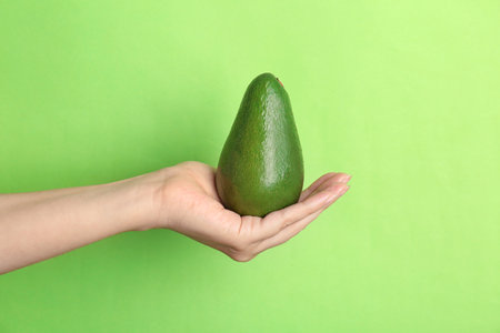 Woman holding ripe avocado on color backgroundの写真素材