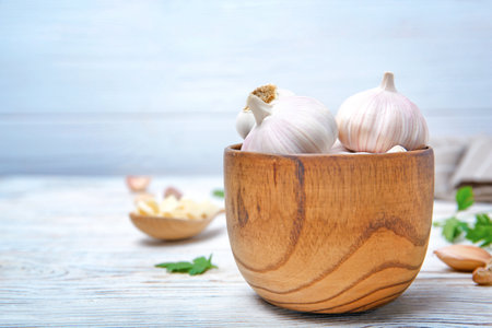 Wooden bowl with fresh garlic bulbs on tableの写真素材