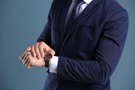Businessman with wrist watch on color background. time conceptの写真素材