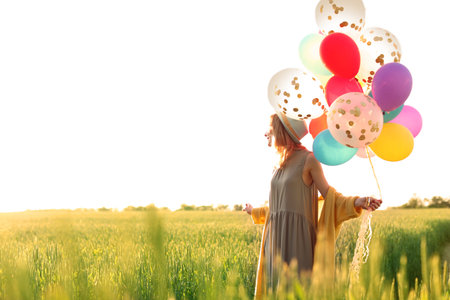 Young woman with colorful balloons outdoors on sunny dayの写真素材