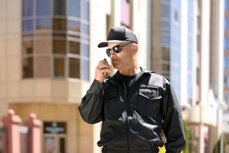 Male security guard using portable radio transmitter outdoorsの写真素材
