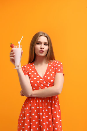 Young woman with glass of delicious milk shake on color backgroundの写真素材