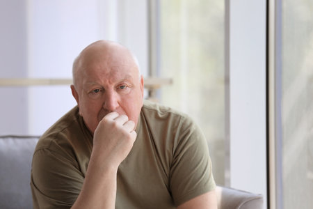Depressed senior man sitting in armchair indoorsの写真素材