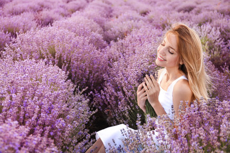 Young woman with bouquet in lavender fieldの写真素材