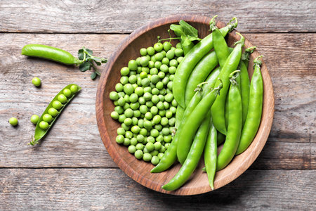 Bowl with delicious fresh green peas on wooden table, top viewの写真素材