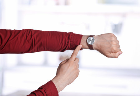 Young man with wristwatch on blurred background, Time conceptの写真素材