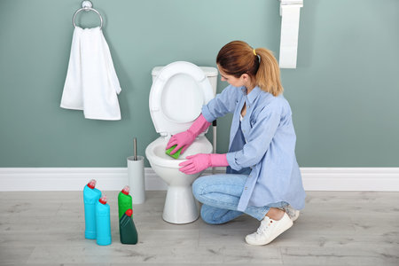 Woman cleaning toilet bowl in bathroomの写真素材