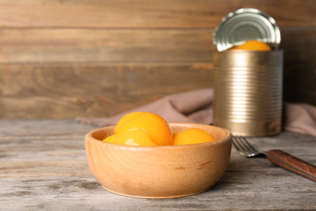 Bowl with canned peaches on wooden tableの写真素材
