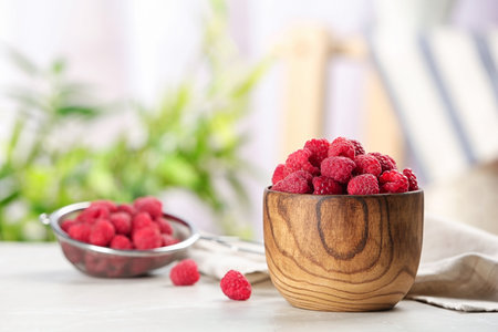 Bowl with ripe aromatic raspberries on tableの写真素材
