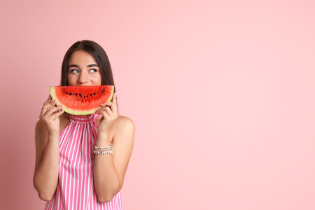 Beautiful young woman posing with watermelon on color backgroundの写真素材