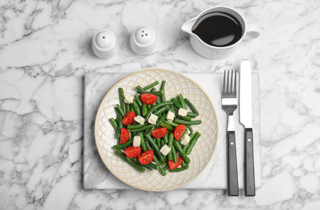 Tasty green beans with cheese and tomatoes served for dinner on marble table, top viewの写真素材