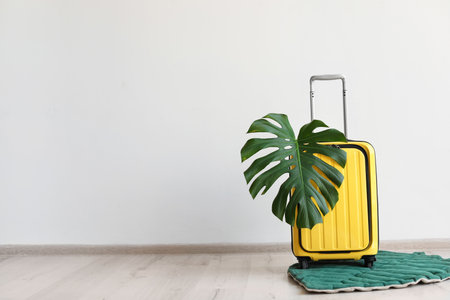 Bright yellow suitcase with tropical leaf indoorsの写真素材