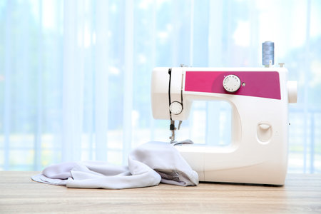 Sewing machine on table near window indoors