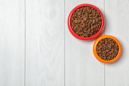 Bowls with food for cat and dog on wooden background. pet careの写真素材