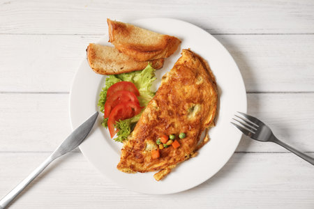 Omelet with vegetables on plate served for breakfast, top view