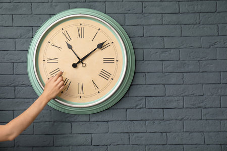 Woman pointing on clock against brick wall. time conceptの写真素材