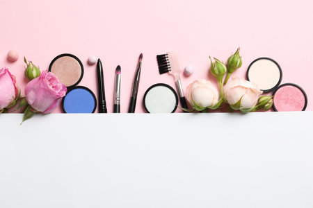 Flat lay composition with card and products for decorative makeup on pastel pink backgroundの写真素材