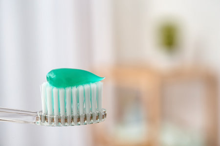Toothbrush with paste on blurred background, closeup