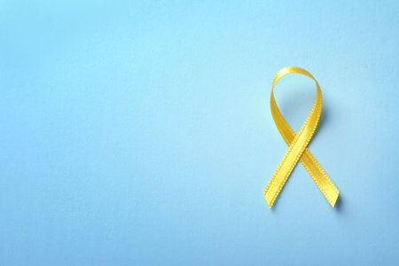 Yellow ribbon on color background, top view. cancer awarenessの写真素材
