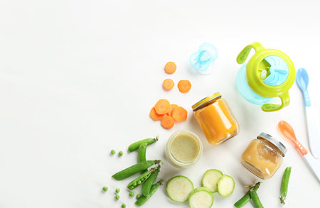 Flat lay composition with baby food, ingredients and accessories on light backgroundの写真素材