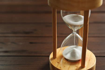 Hourglass with flowing sand on table. time management